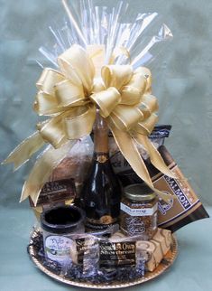 a bottle of wine and some chocolates in a basket with a bow on it