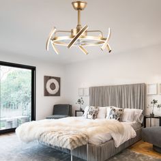 a bedroom with a bed, chair and chandelier hanging from the ceiling in front of a sliding glass door