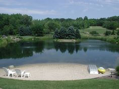 there is a small lake with chairs around it