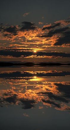 the sun is setting over water with clouds in the sky and reflecting on the water