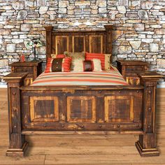 a bed with wooden headboard and foot board in front of a wall made of stone