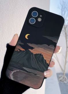 a woman holding up her phone case with an image of the moon and mountains on it