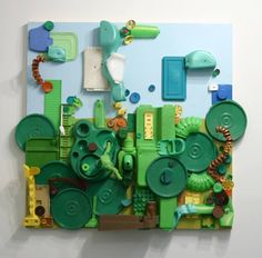 a piece of art made out of green and yellow items on a white wall with blue background