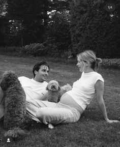 a man and woman sitting on the grass with a dog