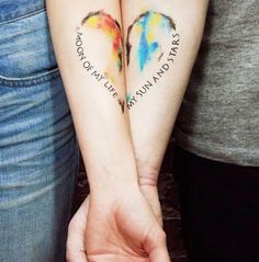 two people are holding hands with tattoos on their arms that say love is in the air