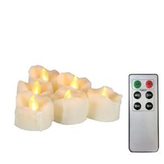 six lit candles with remote control on white background