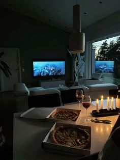 a couple of pizzas sitting on top of a table next to wine glasses and candles