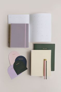 three notebooks, one with a calendar and the other with a pen