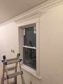 an empty room with a ladder and window in the corner, next to a stepladder