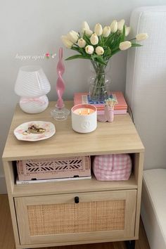 a table with flowers and candles on it next to a white chair in a room