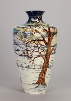 a blue and white vase with a tree painted on the front, sitting against a white background