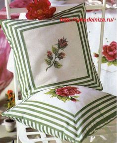 a white chair with a green and white pillow on top of it next to a red flower