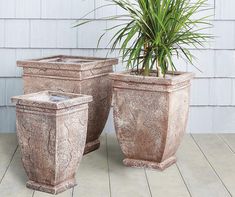 two large planters sitting on top of a wooden floor next to a houseplant