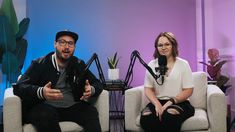 a man and woman sitting on couches in front of a microphone