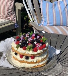 a cake sitting on top of a glass plate covered in berries and strawflowers