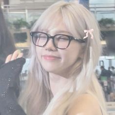 a woman with long blonde hair wearing black glasses and a pink bow in her hair