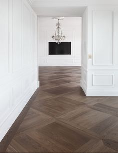 an empty room with white walls and wood flooring is pictured in this image, there is a chandelier hanging from the ceiling