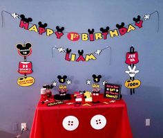 a birthday party with mickey mouse decorations on the wall and red table cloths that say happy birthday