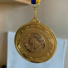 a gold medal with a blue ribbon hanging from it's center circle and the number one on top