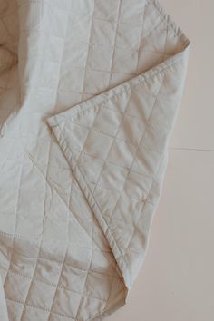 an unmade white quilted blanket laying on top of a bed next to a pillow