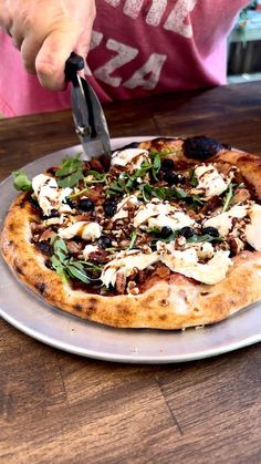 a person cutting into a pizza on top of a metal plate