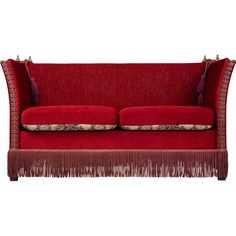 a red couch with fringe trim and pillows on the back, sitting in front of a white background