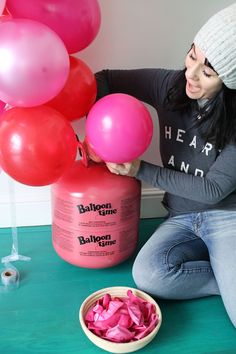 a woman sitting on the floor with balloons in front of her and a canister