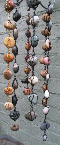 a bunch of different colored stones hanging from a hook on the side of a building