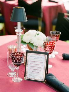 the table is set up with wine glasses and menu cards for guests to sign in