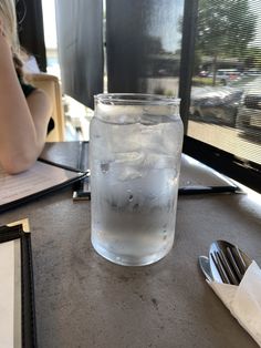 a glass filled with water sitting on top of a table next to utensils