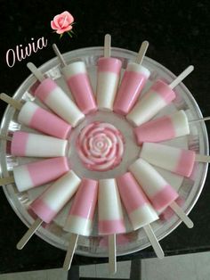 pink and white candy pops arranged in a circle on top of a plate with toothpicks