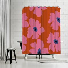 a shower curtain with an orange and pink flower pattern on the side, next to a stool