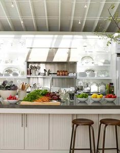 a kitchen filled with lots of counter top space next to two stools in front of an island