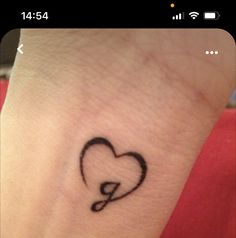 a small black heart tattoo on the wrist