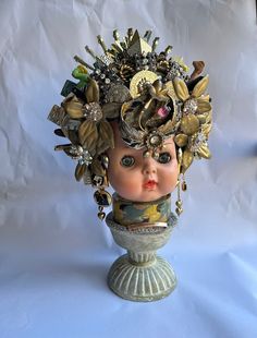 an antique doll head is adorned with gold and jewels