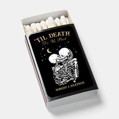 a matchbox filled with white matches and two skulls on top of each other,