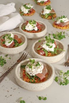 small bowls filled with food sitting on top of a white counter next to utensils