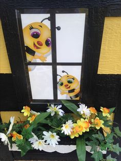 a window sill with flowers in front of it and a paper cut out of a bee