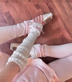 a pair of feet in white shoes and pink pants on a wooden floor next to a woman's leg