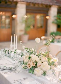 the table is set with white flowers and silverware for an elegant wedding reception in italy