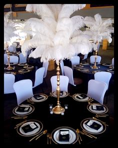 the table is set with white and gold place settings, black linens, and tall centerpieces