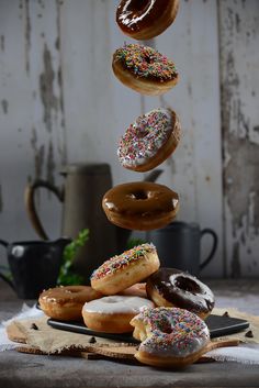 a stack of doughnuts with sprinkles falling from one to the other