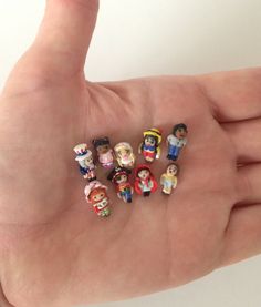 small toy figurines are placed in the palm of a person's hand