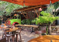 an outdoor dining area with tables, chairs and a truck parked in the back ground