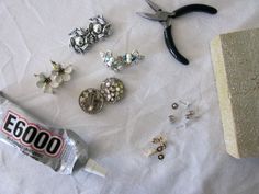 there are many different types of jewelry on the table next to a bottle of glue