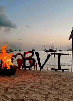 a fire pit sitting on top of a sandy beach next to the words bye written in large letters