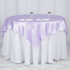 two empty wine glasses are sitting on top of a table with a purple satin overlay