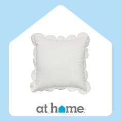 a white pillow sitting on top of a blue and white house shaped pillow with the words at home written below it