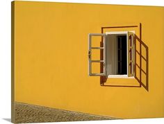 an open window on the side of a yellow wall