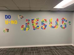 an office wall with the word jesus spelled in multicolored letters on grey walls